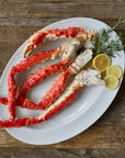 Plated king crab legs with lemon slices and rosemary on a wooden background