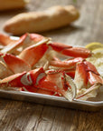 Tray of Dungeness crab legs on a wooden table with lemon wedges
