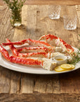 Plated red king crab legs with lemon wedges and rosemary on a wooden table