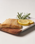 Wild Alaska smoked sablefish served on a wooden board with lemon