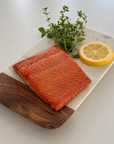 Smoked wild sockeye salmon fillet on a plate with lemon and fresh thyme