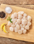Wild Alaska weathervane scallops arranged on a wooden cutting board with lemon