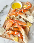 Wild Alaskan Dungeness crab legs on a wooden board with lemon and melted butter