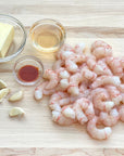 Raw wild alaskan spot prawns with butter, garlic, and oil on a wooden surface