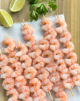 Raw wild Alaskan spot prawn skewers on a tray with lime wedges
