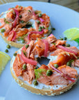 Smoked salmon on top of a toasted bagel with picked onions and cream cheese