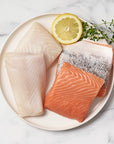 king salmon and halibut on a white plate with a lemon slice