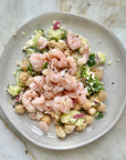 Wild Oregon pink shrimp served over a chickpea salad with cucumber, red onion, herbs and feta on a marble background