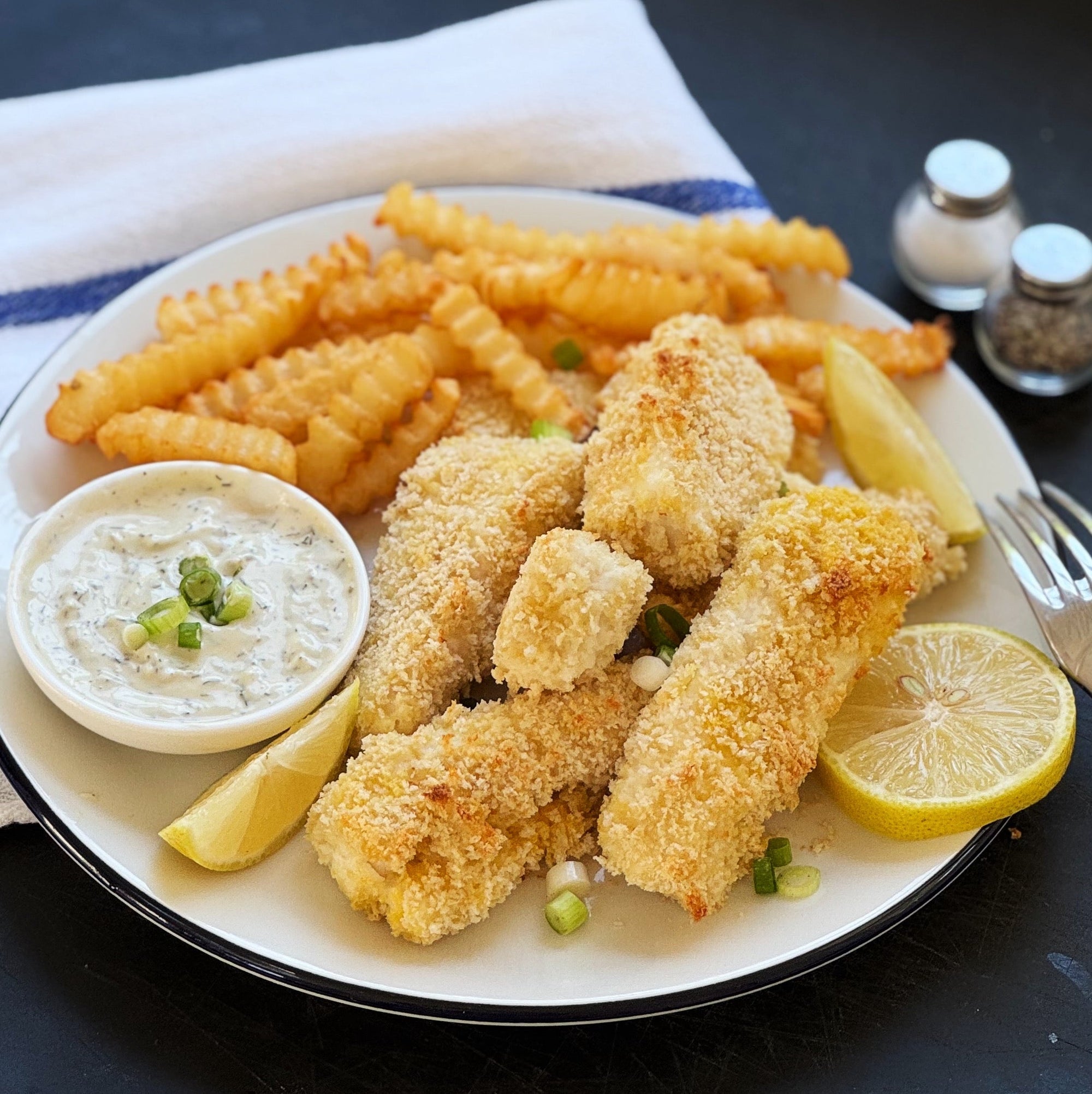 baked fish and chips on a plate with fries and sauce