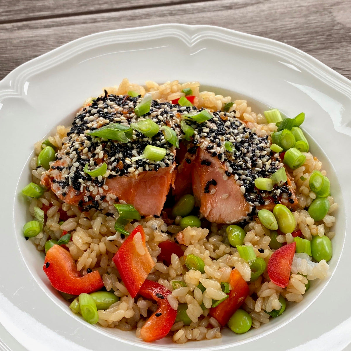 Sesame-crusted salmon sliced over a rice bowl with edamame, red pepper and green onion
