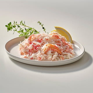 Wild snow crab meat on a plate with lemon wedge and fresh herbs