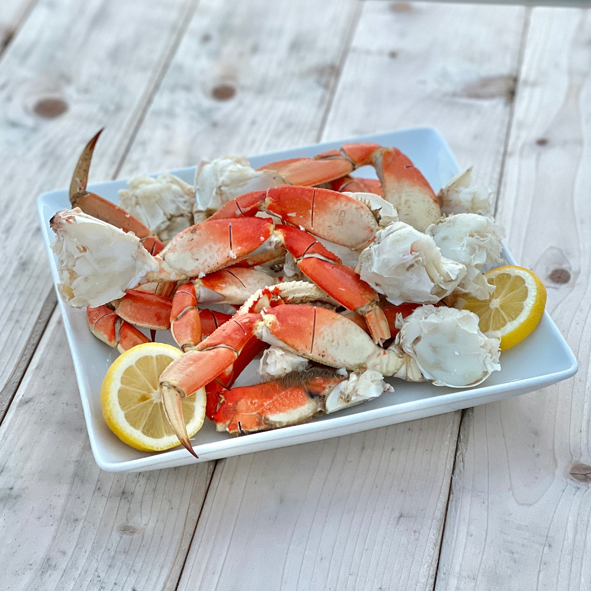 Wild Alaskan Dungeness crab clusters served on a platter with lemon wedges on a dock
