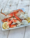 Wild Alaskan Dungeness crab clusters served on a platter with lemon wedges on a dock