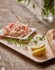 Wild snow crab meat on a plate with lemon wedge and fresh bread on a rustic table