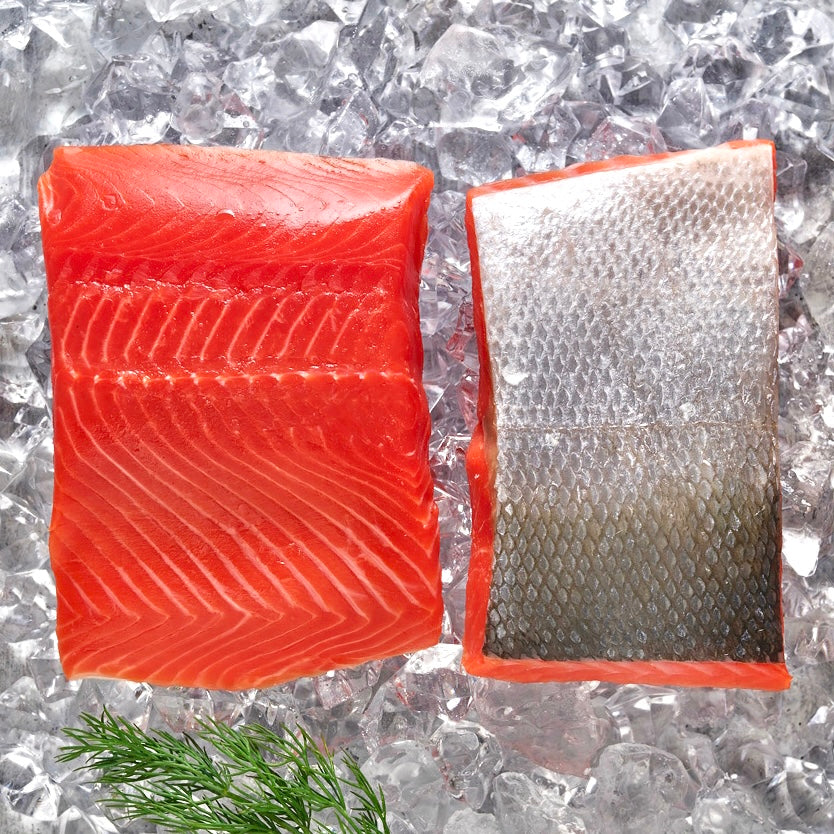 Two portions of sockeye salmon on top of ice with a small sprig of fresh dill.