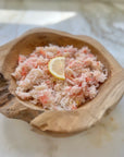 Wild snow crab meat in a wooden bowl with a lemon wedge