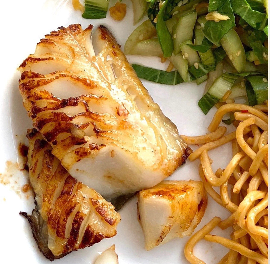Cooked wild sablefish with noodles and bok choy on a white plate