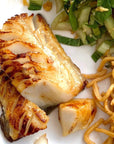 Cooked wild sablefish with noodles and bok choy on a white plate